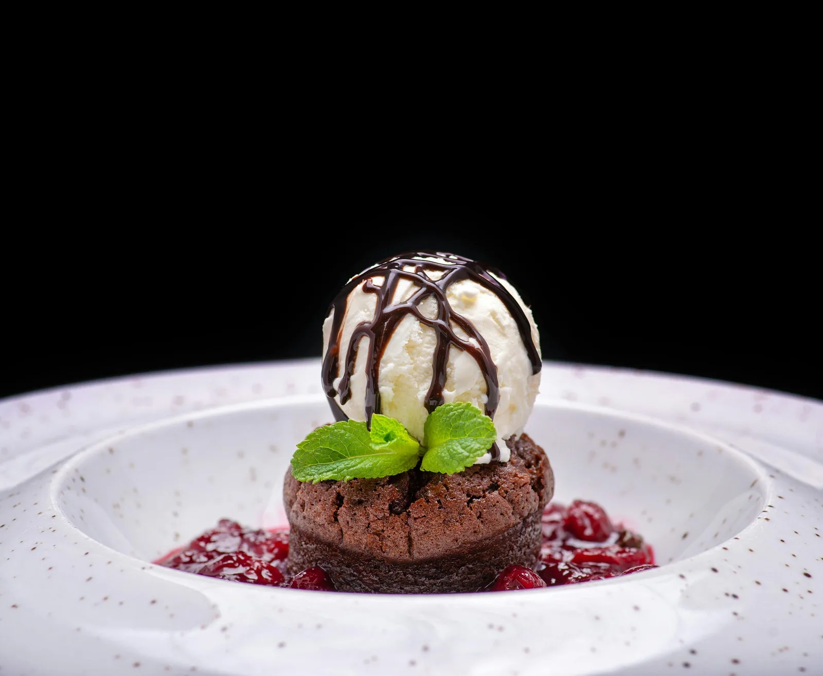 A chocolate lava cake with a scoop of ice cream on a white plate
