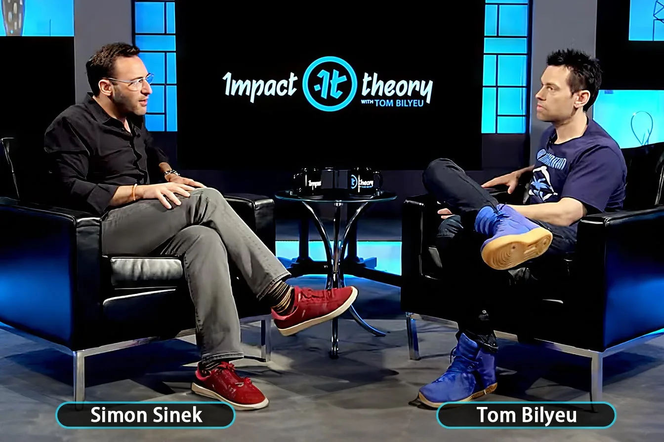 Tom Bilyeu interviewing Simon Sinek across a table on his podcast set
