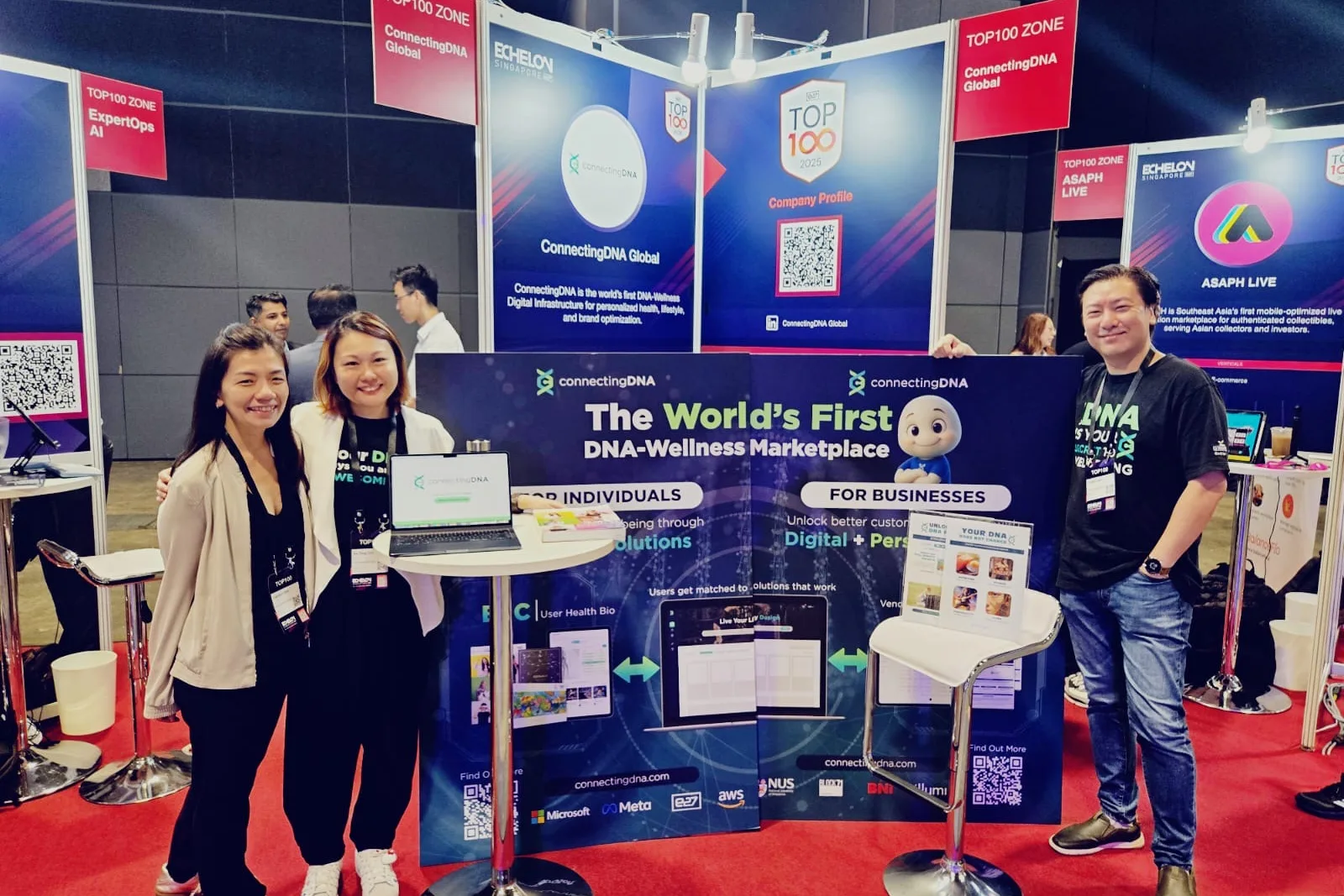 Three of the ConnectingDNA team at their trade-show booth, before a backdrop reading The World's First DNA-Wellness Marketplace, For Individuals and For Businesses