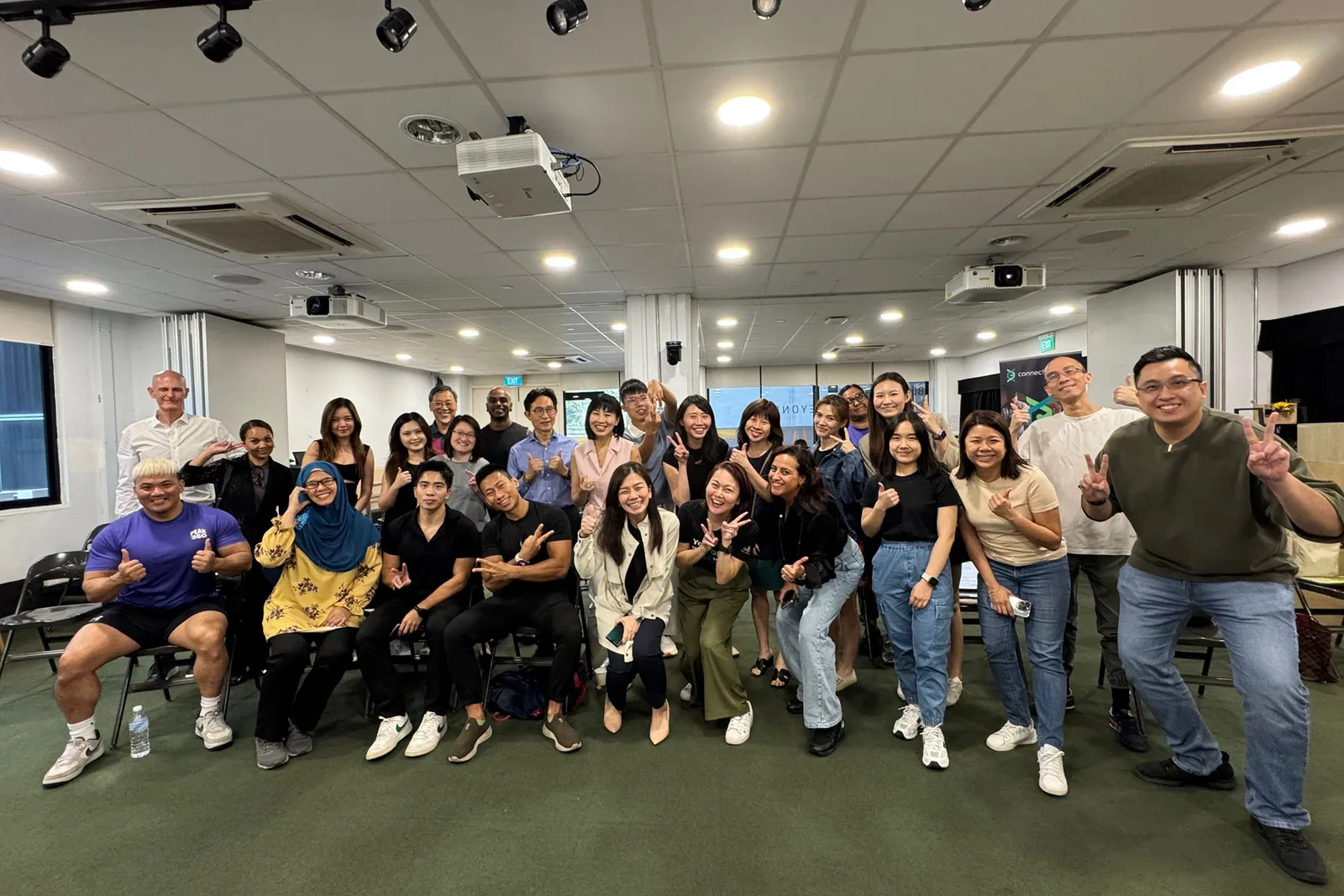 About twenty wellness professionals posing together in a bright meeting room